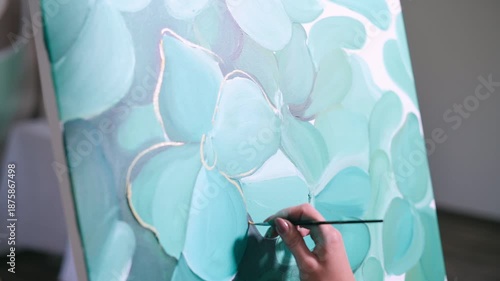 The artist paints a picture. A woman applies paint to a canvas with a brush in the studio. Close-up of hand.