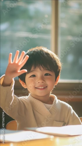 Wallpaper Mural A cheerful young child waving with a smile at the camera in an academic setting, suggesting a positive learning environment. Torontodigital.ca