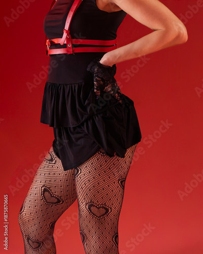 Photography Women's lower body and thighs, showcasing a pair of black fishnet stockings with a distinct heart pattern