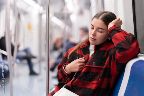 Tableau sur toile During trip to work in tramway car, passenger girl sits and dozes in half-empty tram car