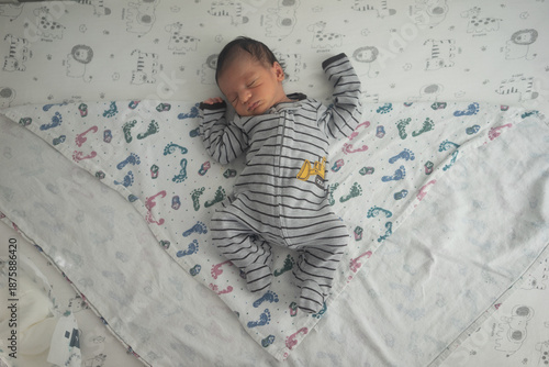 newborn baby laying on patterned blanket