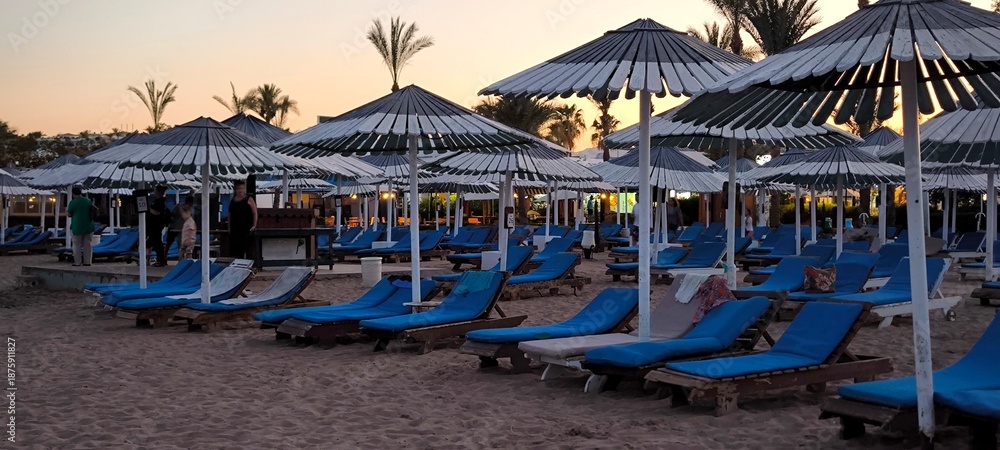 Φωτογραφία Rows of beach umbrellas and sun loungers on the seashore in the evening twilight