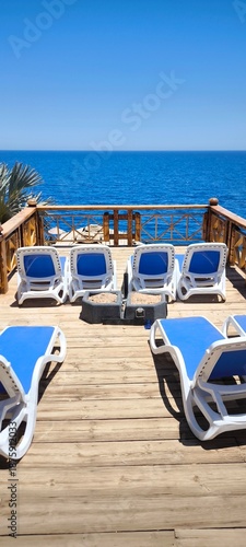A relaxing terrace with blue sun loungers against the backdrop of the bright blue sea