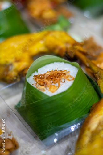 Close-up of Indonesian rice wrapped in banana leaf topped with fried shallots. Traditional Asian food detail with natural packaging and authentic street food style