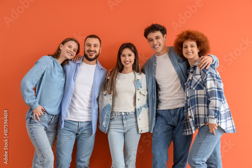 Group of young friends hugging on orange background