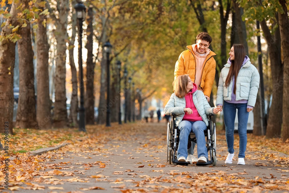 Fototapeta premium Young woman in wheelchair with her friends on autumn day