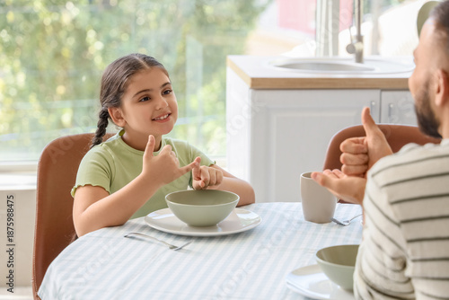 Little girl with her father using sign language in kitchen