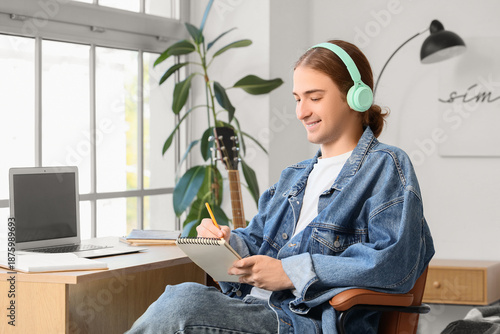 Young man in headphones wri...