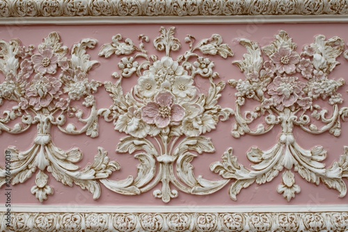 Ornate floral plaster molding features delicate relief patterns against a soft pink background