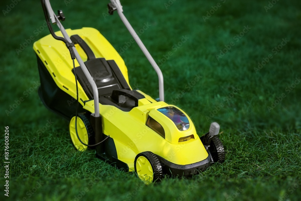 Fototapeta premium Modern lawn mower on green grass outdoors