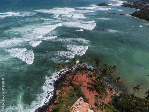 Aerial view of turquoise ocean waves crashing on the rocky coast of Sri Lanka