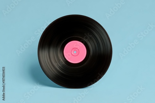 Black vinyl record with pink label centered on light blue background. 