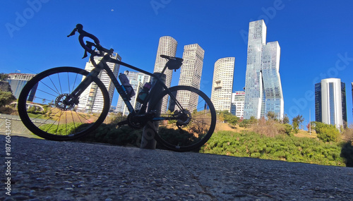 Fotografi Bicycle resting against post in La Mexicana park with Mexico City's Santa Fe fin