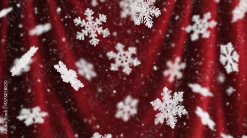 Close-up of intricate white snowflakes falling against a softly draped red fabric backdrop