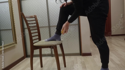 Adult woman brushing dust off black pants indoors. Care for clothes, neat appearance and everyday lifestyle concept.