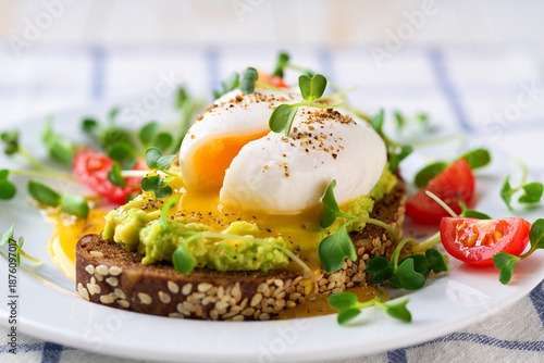 Wallpaper Mural Toast with avocado and egg with cup of tea for healthy breakfast or snack. Sandwich with avocado and poached egg on a white table, selective focus. Torontodigital.ca