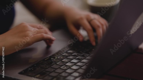 Close up female hands typing on computer sitting in the office. Young women working on laptop at home while drinking coffee at home. Technology lifestyle concept. Woman typing on laptop.