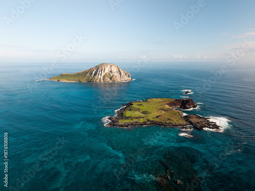 Aerial drone footage moving toward small tropical islands surrounded by clear blue ocean, showcasing rugged coastline, turquoise water, and remote island seascape in a peaceful natural environment