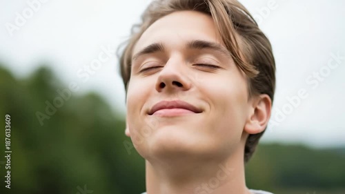 Young man with hands behind head looking up at the sky with a smile.