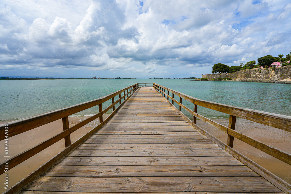 Fototapeta premium Wooden pier on the beach of the Puerta de San Juan in Puerto Rico - Coastal colonial fortifications in the Caribbean Sea