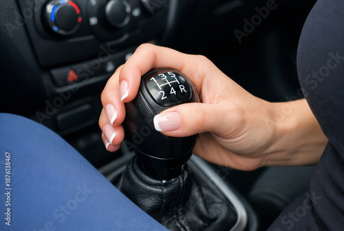 Close-up of a woman's hand shifting gears in a manual transmission car.
