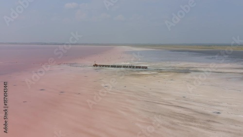 Burlinskoye Lake (Bursol), Altai Krai — Pink Salt Lake. A train‑like vehicle moves along the shore.