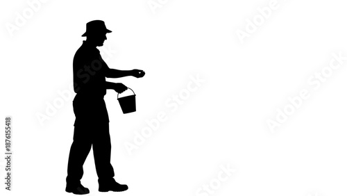 Man in hat holding bucket and walking alone in silhouette against a white background