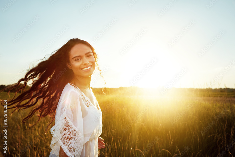 Fototapeta premium Portrait, woman and happy in field for travel adventure, summer holiday and fresh air. Space, smile and female person with lens flare in meadow, explore nature and vacation getaway in countryside