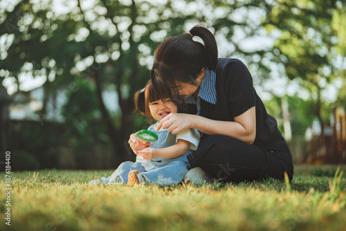 Foto Happy Asian mother and toddler daughter exploring nature with a magnifying glass