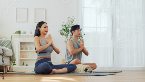 Asian man and woman relax with meditation pose, enjoying calm yoga moment and healthy lifestyle indoors