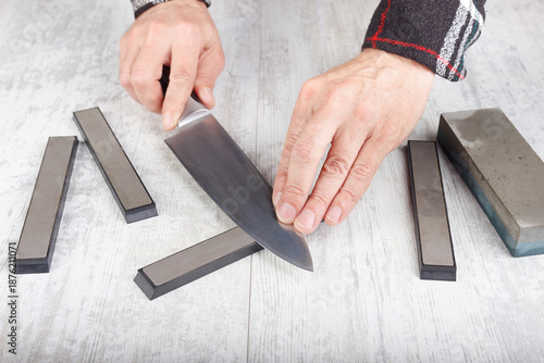 Sharpening chef's knife on white table.