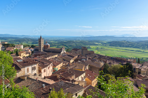 Panoramic view of Massa Marittima, Italy, featuring the Cathedral of Saint Cerbonius and the Maremma landscape under a clear blue sky. Tuscan town