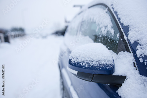 Details of a blue car covered in snow. Heavy snowing, transportation and road cleaning. 