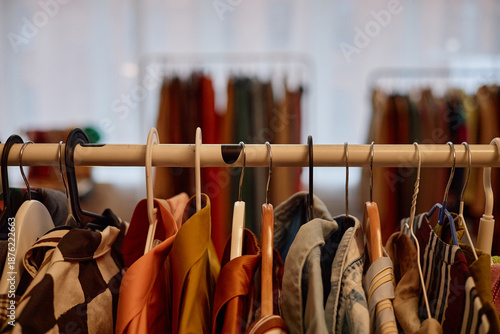 Φωτογραφία Assorted second hand clothing hanging on rack in store, various garments display