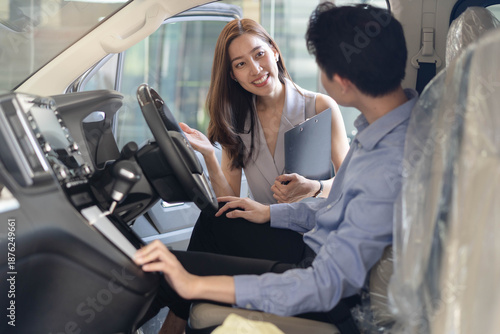 Foto Woman car salesperson showing finance contract to client and explain deal in aut