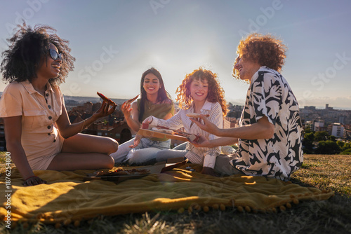 Canvas Print Diverse friends enjoying outdoor picnic laughing and eating pizza