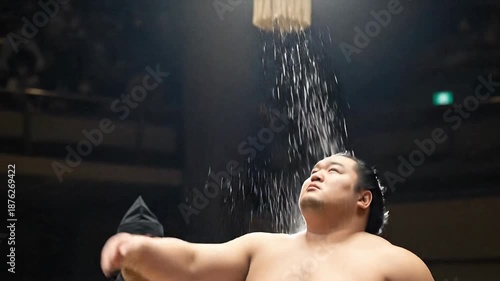 Sumo wrestler throwing salt with referee in background