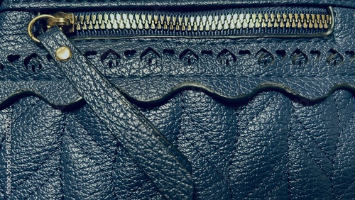 Close-up of blue leather texture with zipper and stitched decorative trim.