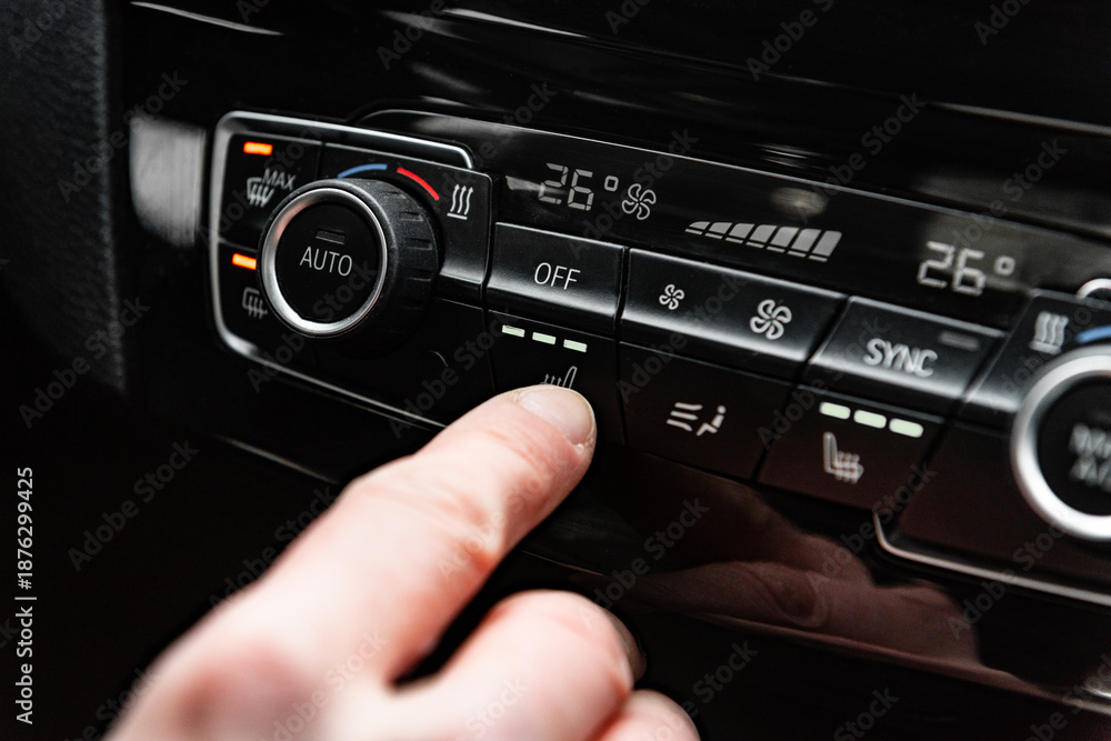 Fototapeta premium Hand pressing the button for interior heating and heated seats in the car in winter.