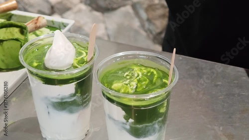 Spoon whipped cream onto a pour of concentrated Japanese matcha into a glass filled with whipped cream.