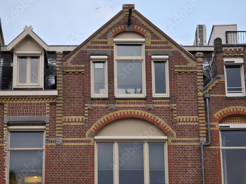 Wallpaper Mural A brick building facade typical of Amsterdam, featuring detailed yellow-striped brickwork, diverse window styles including arched ones, and pitched roofs with dormers and skylights Torontodigital.ca