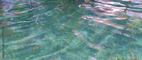 Abstract water surface texture with gentle ripples and soft natural light reflections creating calm organic visual pattern. Nature background concept