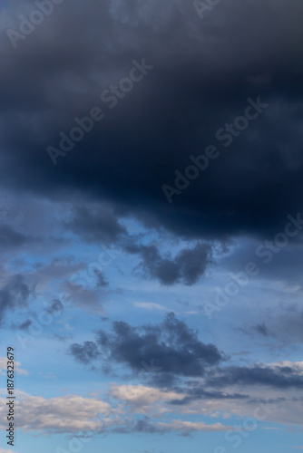 Dramatic Dark Storm Clouds Over Blue Sky With Light Breaks And Quiet Horizon