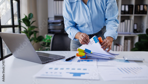 Businesswoman hands working in Stacks of paper files for searching and checking unfinished document achieves on folders papers at busy work desk office

