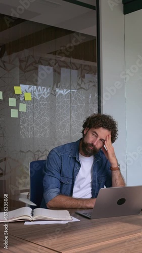 Stressed businessman experiencing burnout and headache at office desk