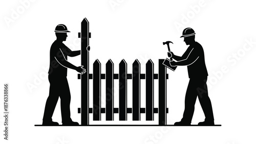 Two construction workers in hard hats installing a wooden picket fence outdoors