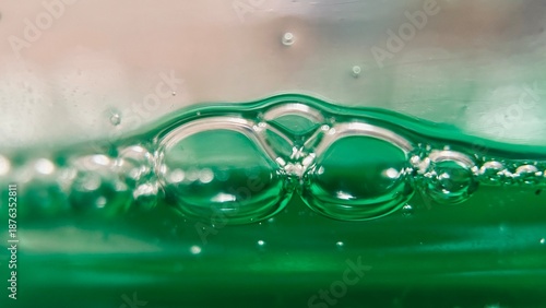 Macro close-up of bubbles formed on green liquid dishwashing soap.