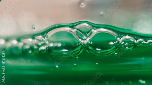 Macro close-up of bubbles formed on green liquid dishwashing soap.