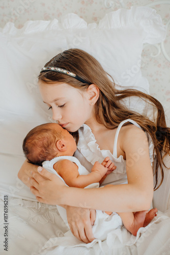 Schilderij op canvas Sister holds newborn baby in quiet moment at home