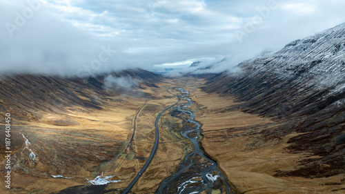 Aerial View of Remote Icelandic Valley with Meandering River and Mountain Road Surrounded by Mist and Volcanic Highlands